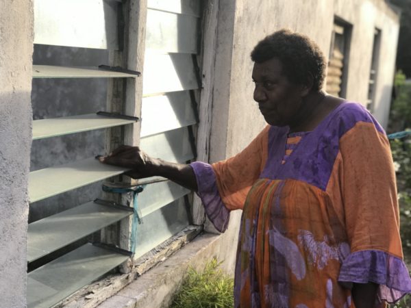 Dorothy looks through the windows of her old home, which was heavily damaged during Cyclone Pam.